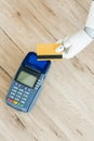 top view of hand of robot holding credit card above payment terminal on wooden Royalty Free Stock Photo